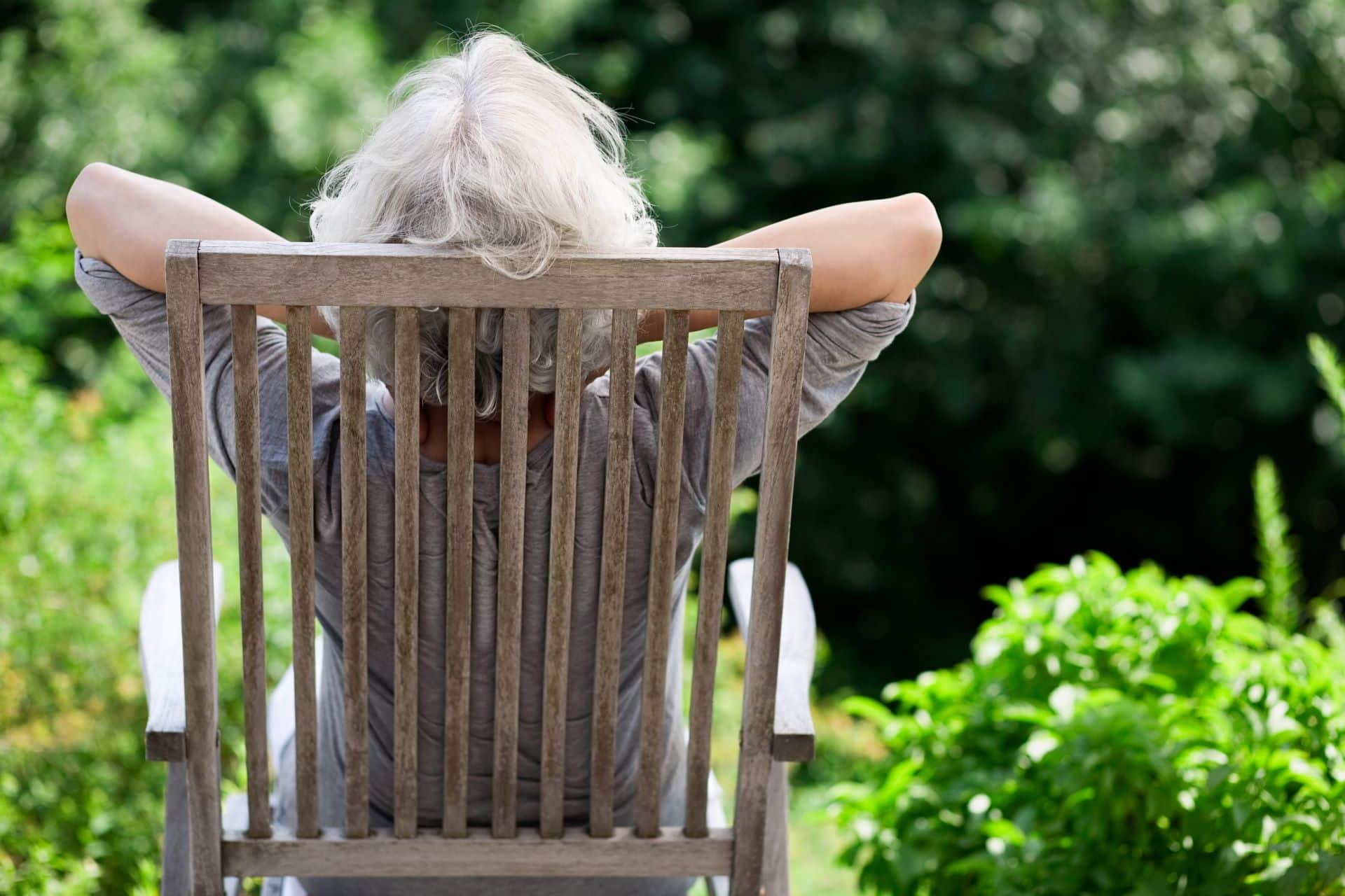 grauhaarige Frau entspannt im Garten