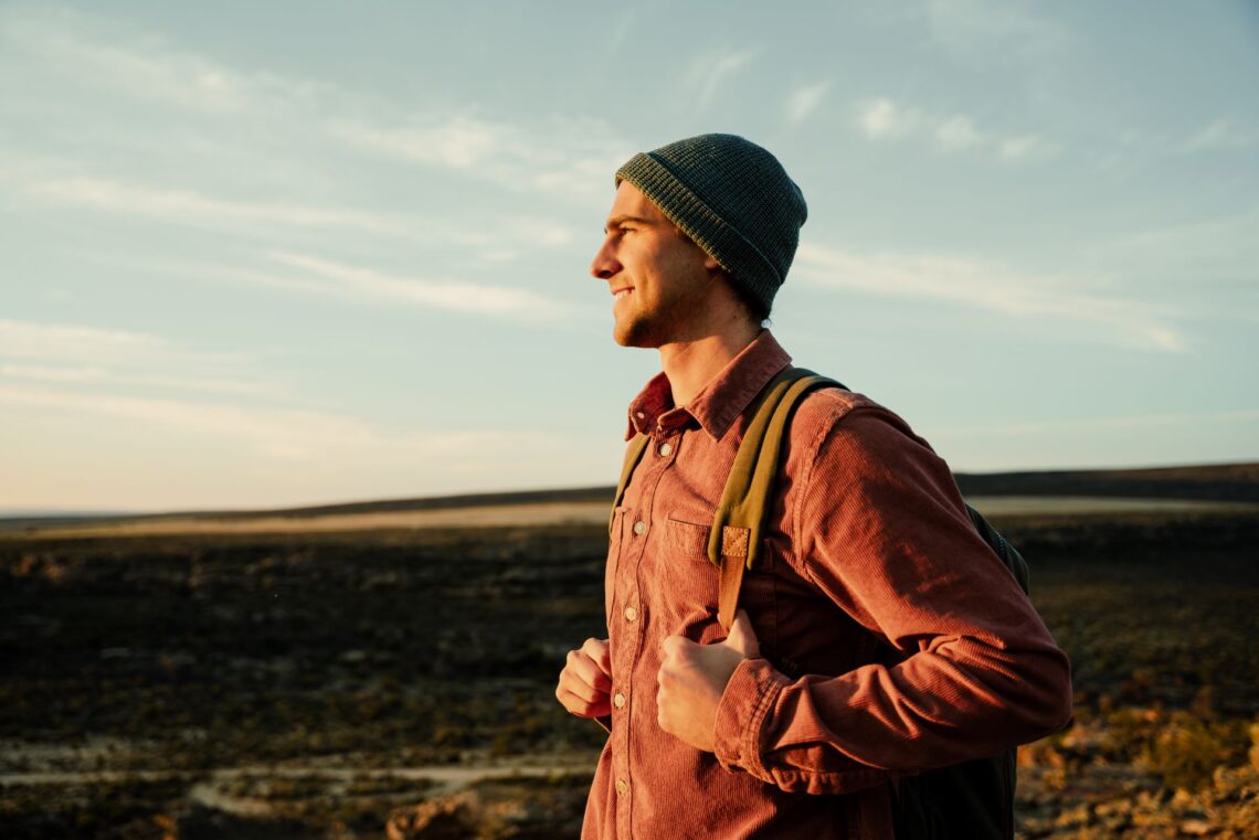 Ein Wanderer genießt den Sonnenaufgang mit einem Rucksack auf dem Rücken, bereit für das nächste Abenteuer – perfekt ausgestattet, inklusive des richtigen Taschenmessers für unterwegs.