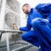 Technician in blue uniform measuring the temperature of an HVAC unit to ensure proper function of airflow sensors