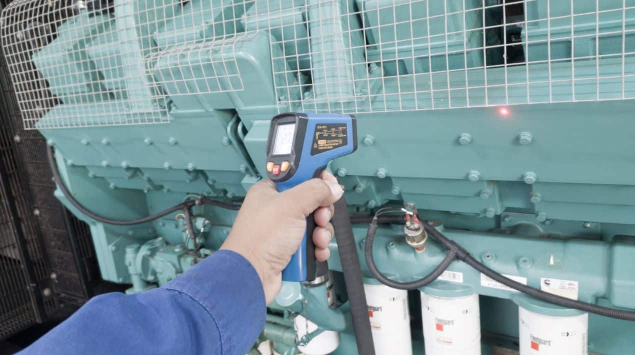 Person using an infrared thermometer to measure the temperature on industrial equipment with airflow sensors