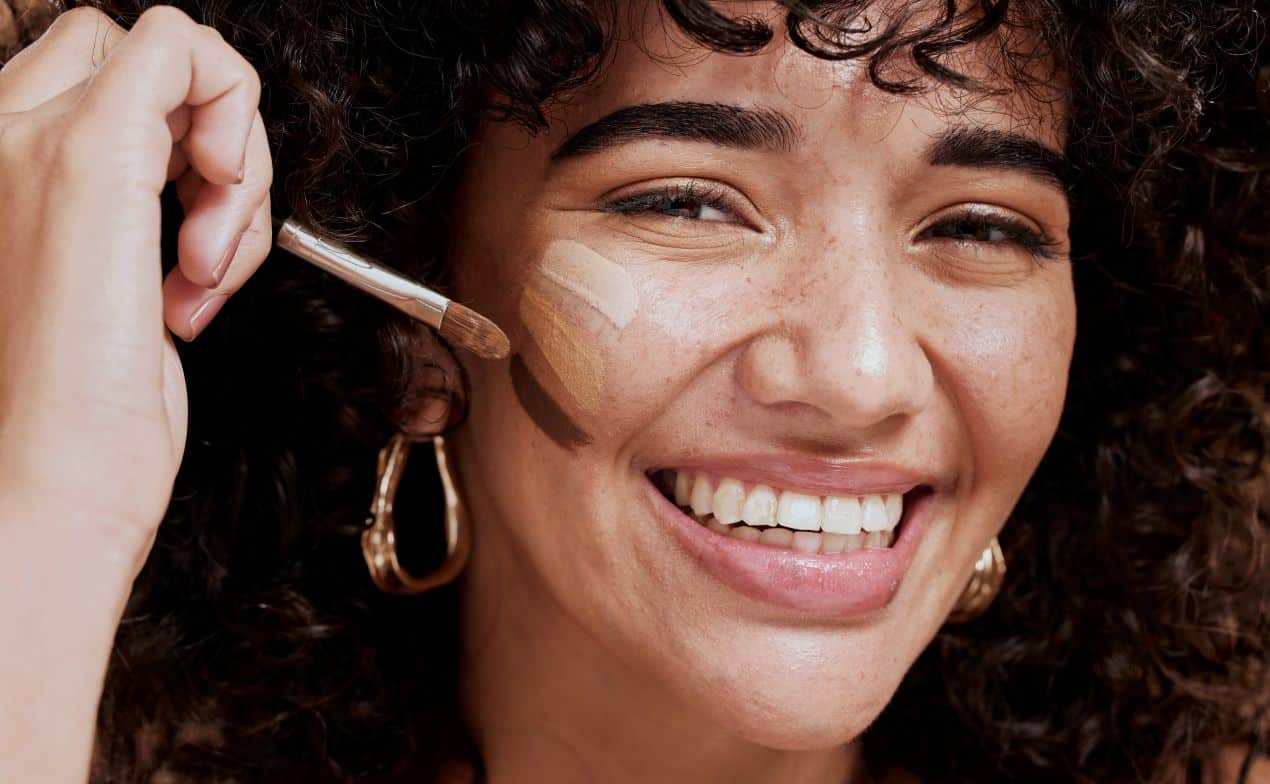 junge frau traegt jane iredale foundation mit pinsel auf ihr gesicht auf