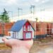 Hausmodell auf Hand vor Neubau | Scherenbühnen mieten