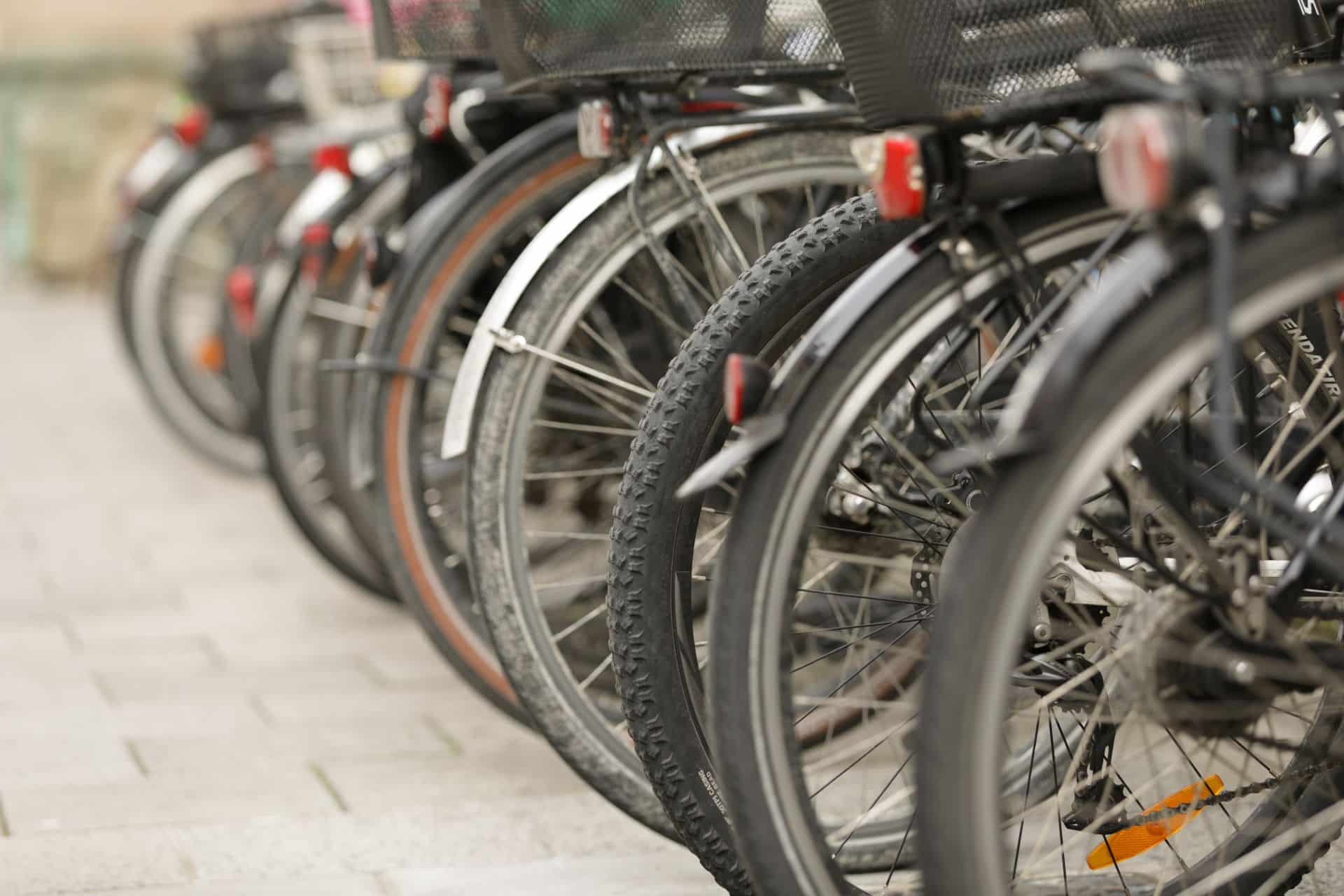 Nahaufnahme von geparkten Fahrradrädern auf Pflaster ohne Wetterschutz – zeigt den Bedarf einer Fahrradgarage im Alltag.