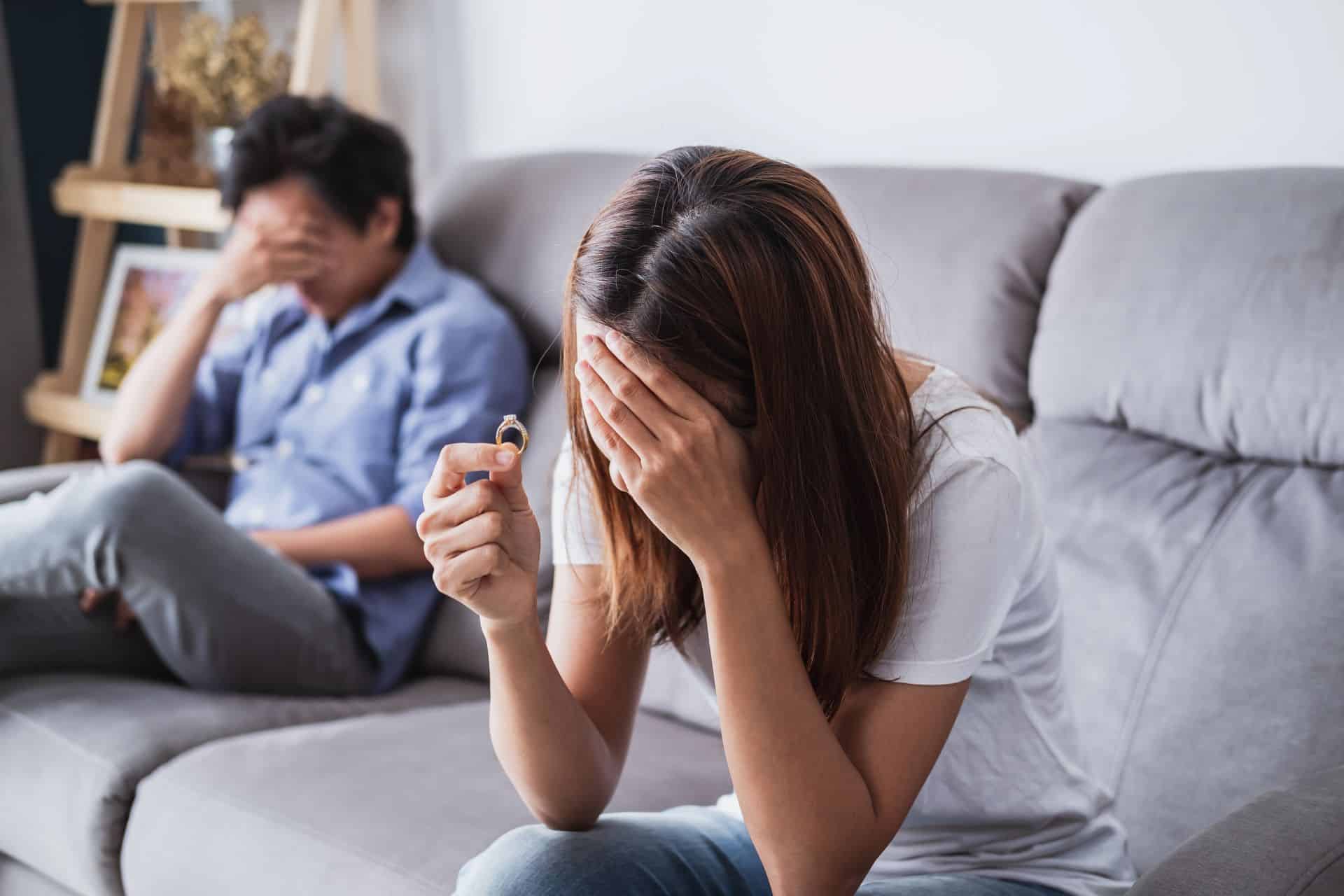 Frau mit Ehering weinend auf Sofa