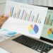 Person analysiert bunte Diagramme mit Finanzdaten | Lohnabrechnung online