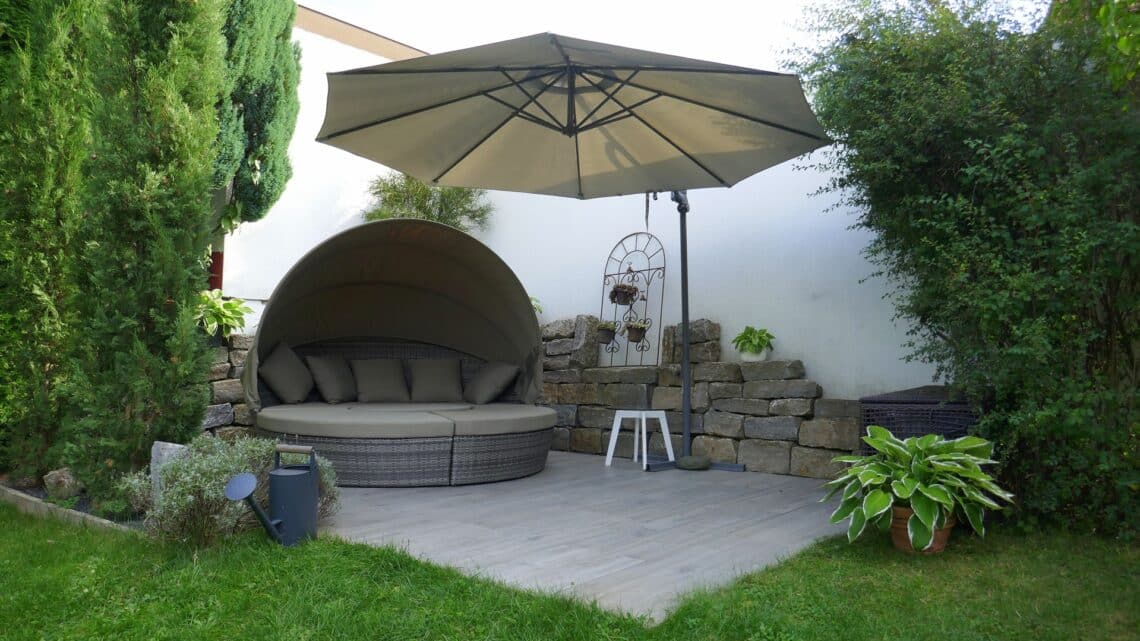 Gemütliche Outdoor-Lounge mit Schirm und Steinmauer | Poolschlauch