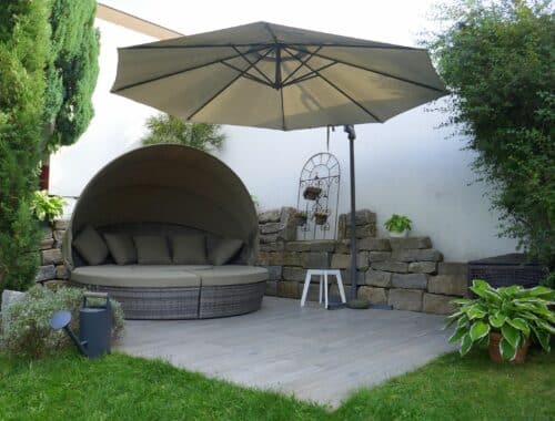Gemütliche Outdoor-Lounge mit Schirm und Steinmauer | Poolschlauch